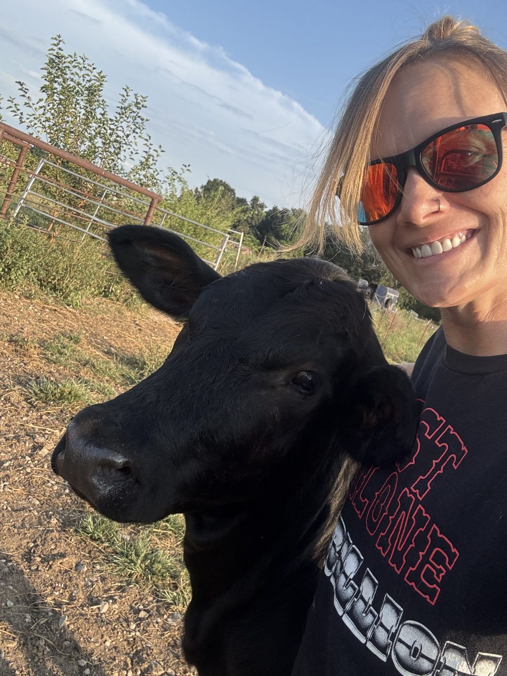 DeNora smiling in a selfie with a black calf